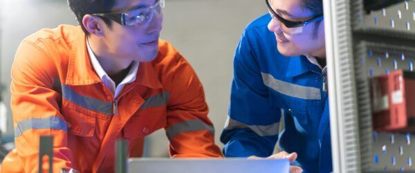 Engineers collaborating on factory machinery.