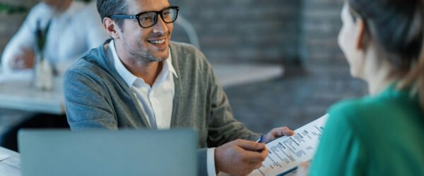 happy-businessman-talking-to-his-colleague-while-going-through-financial-reports