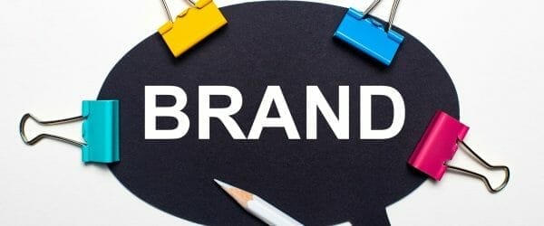 light surface multi colored paper clips white pencil black paper with words brand 1