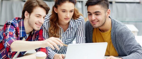 Three students collaborating on laptop